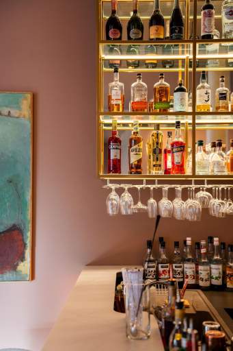 Détail des étagères rétroéclairées du bar avec verres suspendus et bouteilles alignées, bar du restaurant L'Assiette Normande à Honfleur