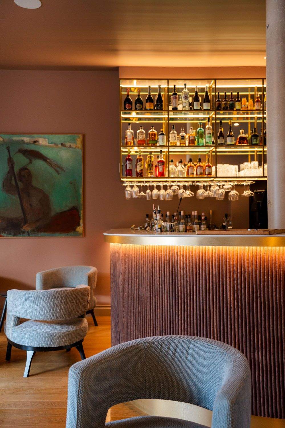 Comptoir de bar avec étagères dorées garnies de spiritueux et fauteuil en velours, bar honfleur centre ville