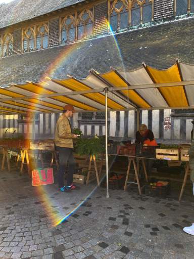 Stand de marché sous auvent jaune avec arc-en-ciel, producteurs locaux à Honfleur de L'Assiette Normande