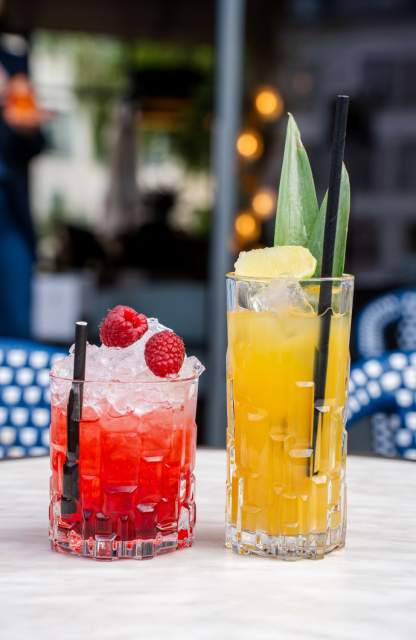 Deux cocktails colorés, un rouge aux framboises et un jaune à l'ananas, servis en terrasse café Honfleur, restaurant L'Assiette Normande