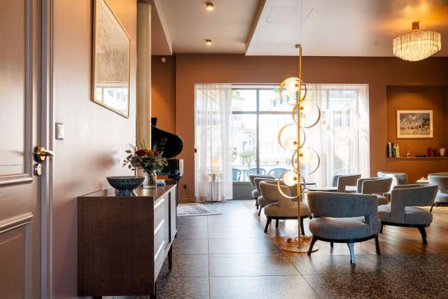 Hall d'accueil lumineux avec lustre doré en cascade, buffet et fauteuils, hôtel Invitation au Voyage Honfleur