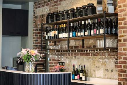 Étagères de vins et bouteilles de champagne derrière un comptoir en briques apparentes, bar du restaurant L'Assiette Normande à Honfleur