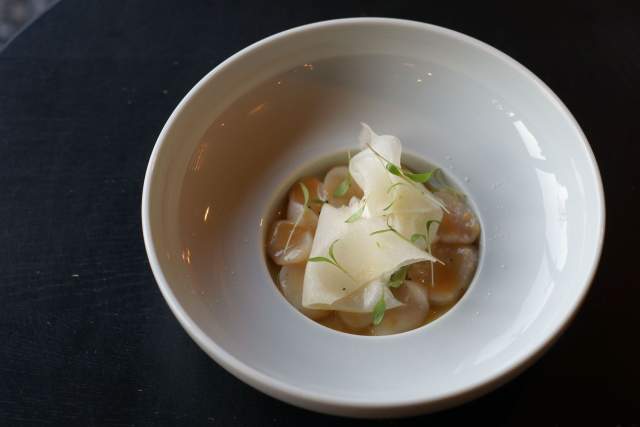 Bouillon clair avec copeaux de fromage et herbes fraîches dans un bol blanc, spécialité normande servie chaude, restaurant L'Assiette Normande à Honfleur