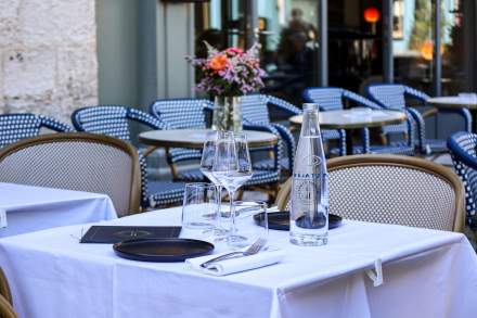 Table en terrasse du restaurant L'Assiette Normande dressée avec nappe blanche, verres et carafe d'eau, où manger à Honfleur en plein air