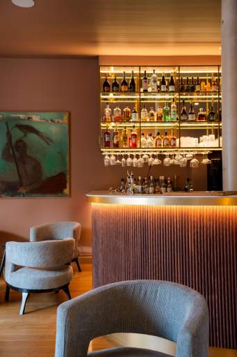 Comptoir de bar avec étagères rétroéclairées et large sélection de bouteilles, bar du restaurant L'Assiette Normande à Honfleur à l'ambiance feutrée
