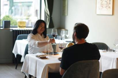 Deux convives portant un toast au verre de vin rouge en salle de restaurant L'Assiette Normande, où manger à Honfleur
