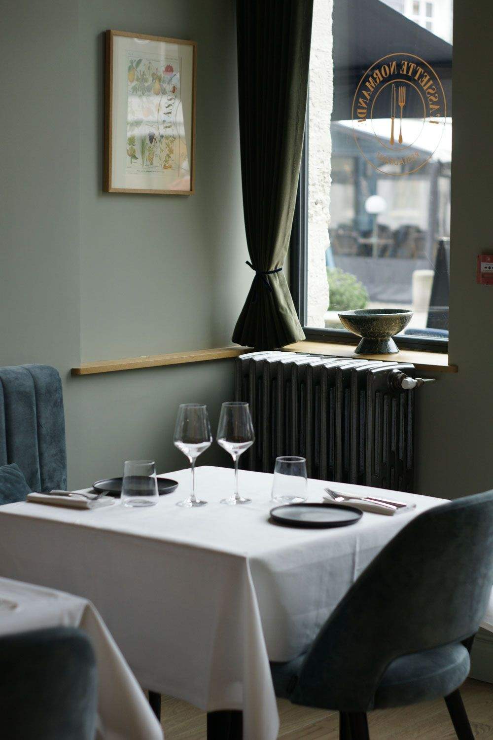 Table dressée avec verres à pied et radiateur en fonte près d'une fenêtre, salle du restaurant bistronomique Honfleur