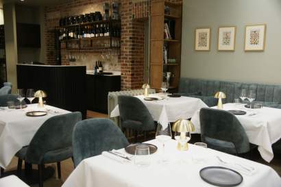 Salle de restaurant avec tables dressées, fauteuils velours gris et mur en briques apparentes, bistronomique L'Assiette Normande à Honfleur