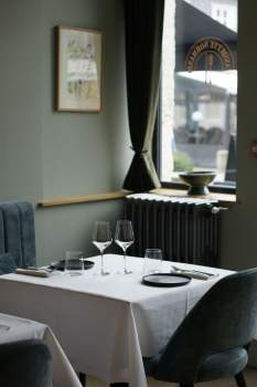 Table dressée avec verres à pied et nappe blanche près d'une fenêtre, salle du restaurant bistronomique L'Assiette Normande à Honfleur