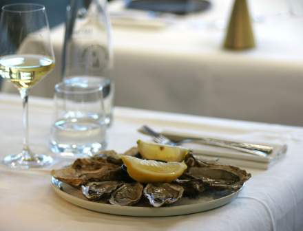 Assiette d'huîtres fraîches avec quartiers de citron et pain grillé, fruit de mer Honfleur accompagné d'un verre de vin blanc du restaurant L'Assiette Normande à Honfleur