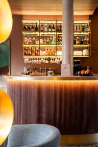 Comptoir du bar avec éclairage chaud, étagères garnies et verrerie suspendue, bar bistronomique du restaurant L'Assiette Normande à Honfleur