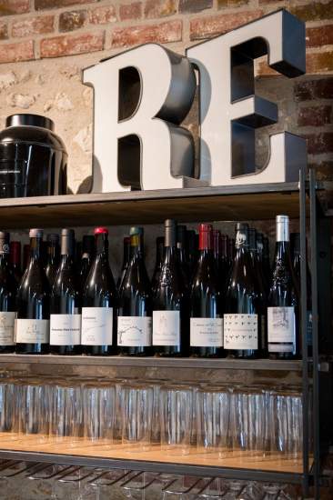 Étagères de vins et bouteilles de champagne derrière un comptoir en briques apparentes, bar du restaurant L'Assiette Normande à Honfleur