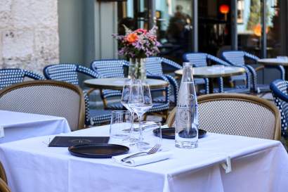 Table de terrasse dressée avec nappe blanche, verres et carafe, petit déjeuner Honfleur en plein air, restaurant L'Assiette Normande