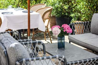Terrasse extérieure avec mobilier de jardin, parasol et fleurs roses en pot, restaurant bistronomique L'Assiette Normande bord de mer à Honfleur