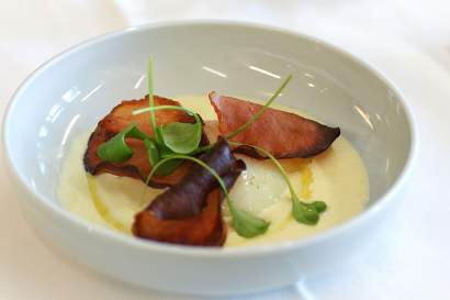 Assiette creuse avec velouté crémeux, morceaux de poisson fumé et pousses vertes, spécialité normande en entrée du restaurant bistronomique L'Assiette Normande à Honfleur