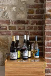 Cinq bouteilles de vins naturels et verres à dégustation sur présentoir en bois, sélection vins restaurant L'Assiette Normande à Honfleur