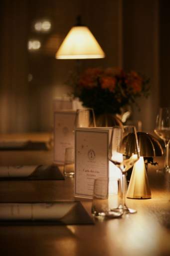 Table dressée en soirée avec carte du menu, bougie et verre à vin sous lumière chaude, restaurant L'Assiette Normande à Honfleur